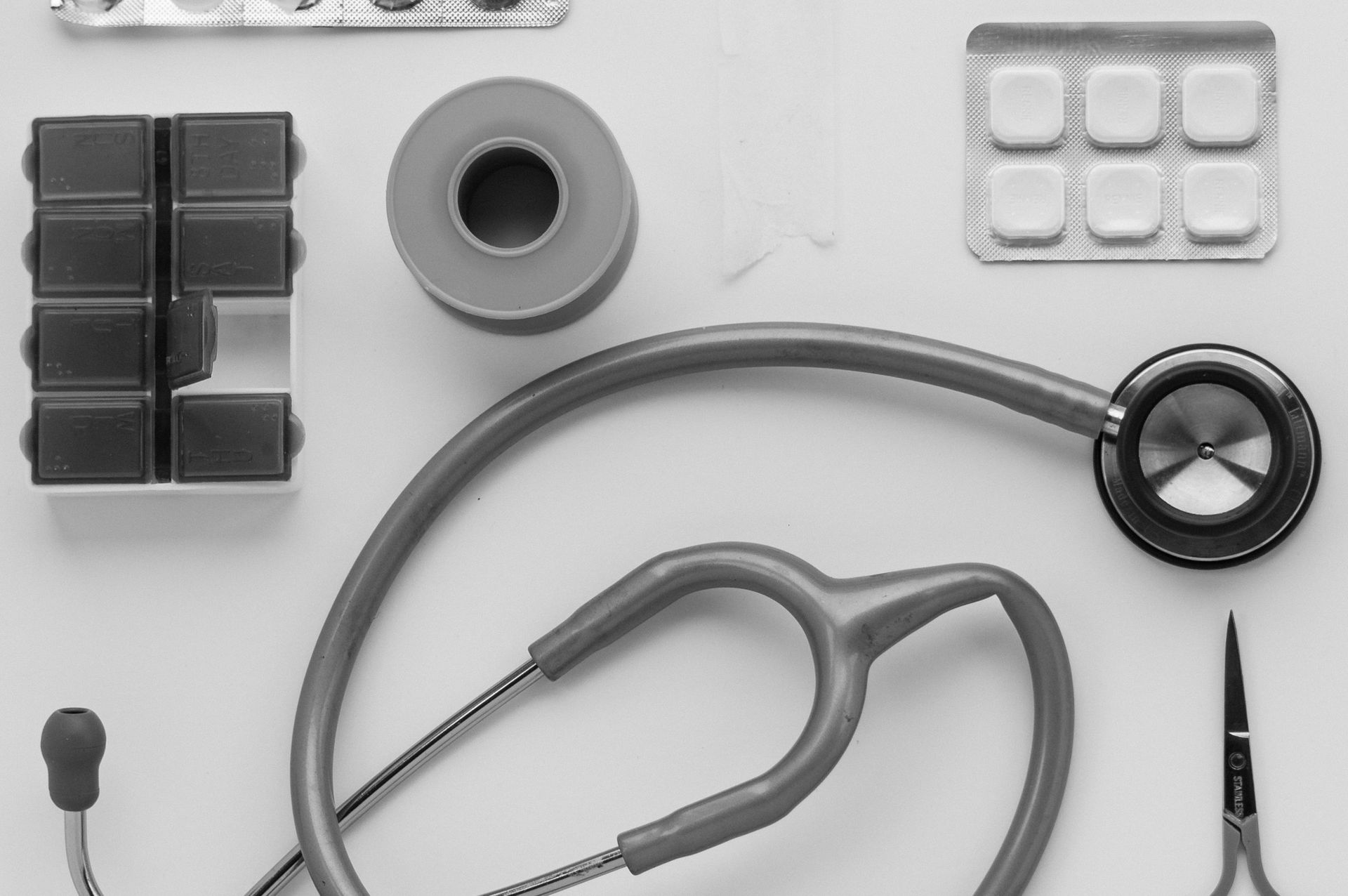 Top view of medical instruments and pills arranged on a white background.